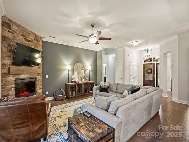 living room featuring dark hardwood / wood-style floors, ornamental molding, a fireplace, and ceiling fan with notable chandelier