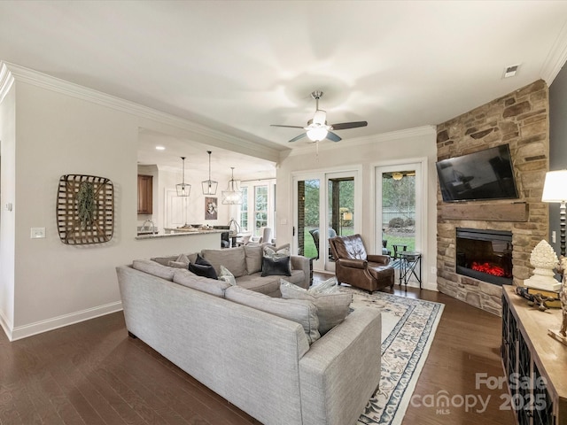 living room featuring a fireplace, dark wood-type flooring, ceiling fan, and crown molding