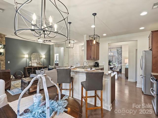 kitchen featuring dark wood-type flooring, stainless steel appliances, light stone counters, a notable chandelier, and kitchen peninsula