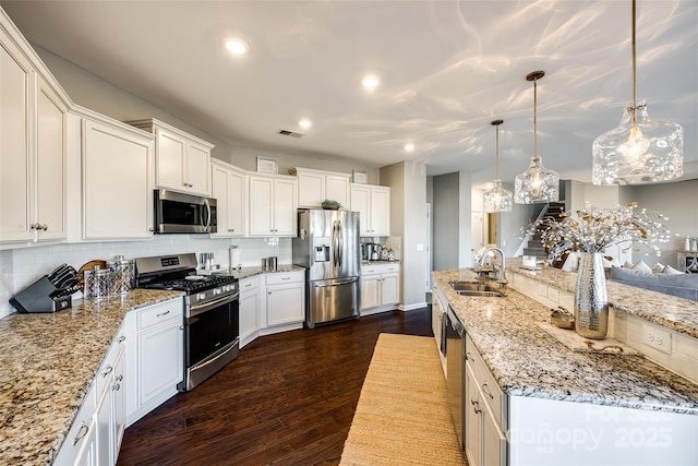 kitchen with sink, backsplash, decorative light fixtures, white cabinets, and appliances with stainless steel finishes