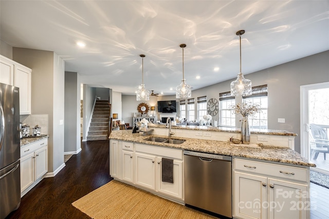 kitchen with sink, appliances with stainless steel finishes, tasteful backsplash, decorative light fixtures, and white cabinetry