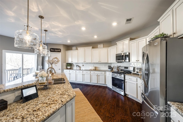 kitchen featuring backsplash, dark wood-type flooring, sink, appliances with stainless steel finishes, and decorative light fixtures