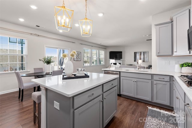 kitchen with sink, gray cabinetry, dark hardwood / wood-style floors, decorative backsplash, and decorative light fixtures