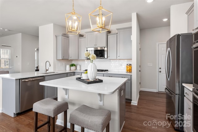 kitchen featuring sink, decorative light fixtures, dark wood-type flooring, and stainless steel appliances