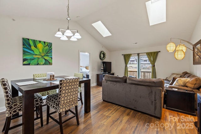 dining space with wood-type flooring, a notable chandelier, and vaulted ceiling with skylight