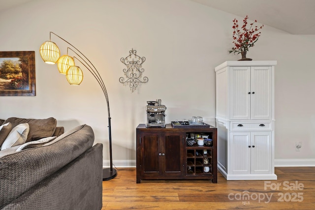 interior space with hardwood / wood-style floors, white cabinetry, and vaulted ceiling