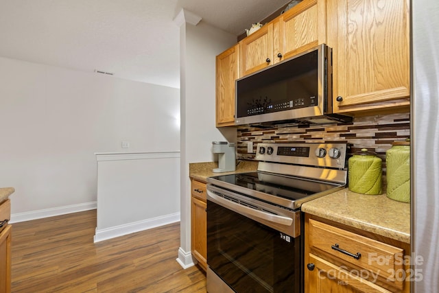 kitchen featuring backsplash, light brown cabinetry, dark wood-type flooring, and appliances with stainless steel finishes