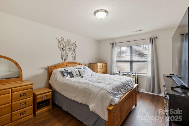 bedroom featuring dark hardwood / wood-style flooring and a textured ceiling