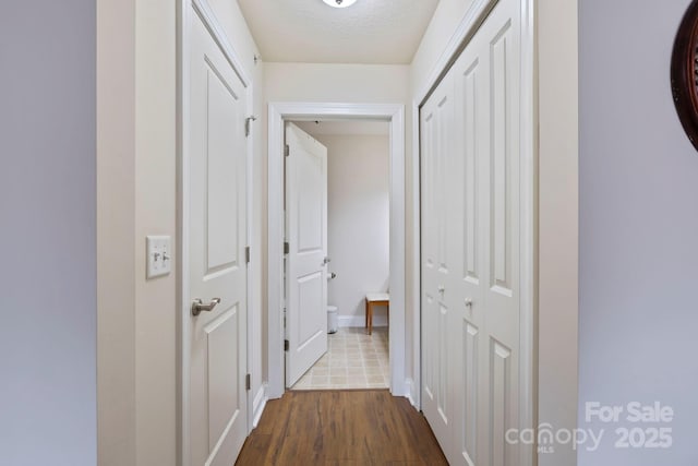 hallway with hardwood / wood-style floors and a textured ceiling