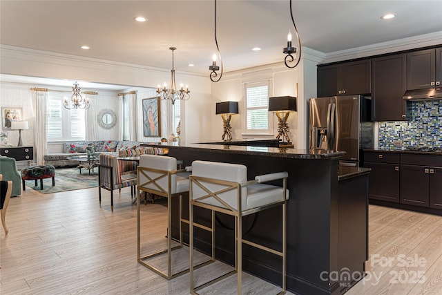 kitchen featuring stainless steel fridge, a kitchen breakfast bar, pendant lighting, light hardwood / wood-style flooring, and a kitchen island