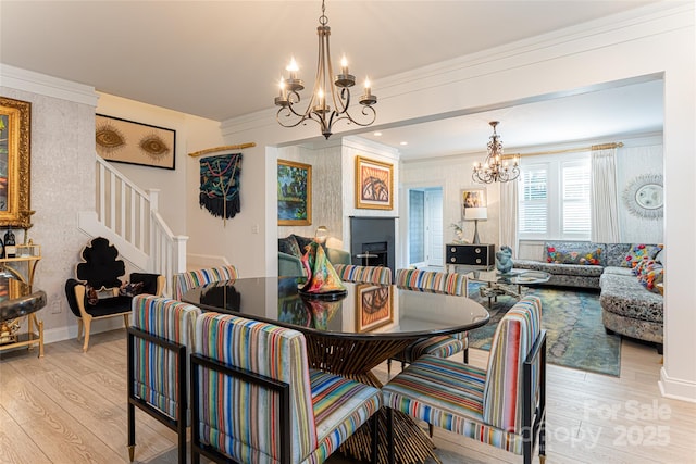 dining area with crown molding, a chandelier, and light wood-type flooring