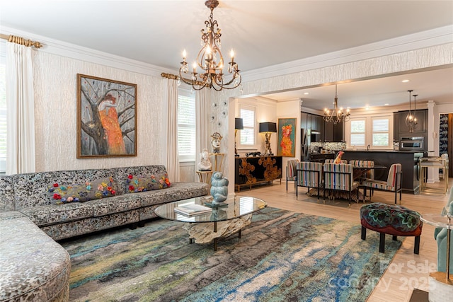 living room featuring light wood-type flooring, ornamental molding, and an inviting chandelier