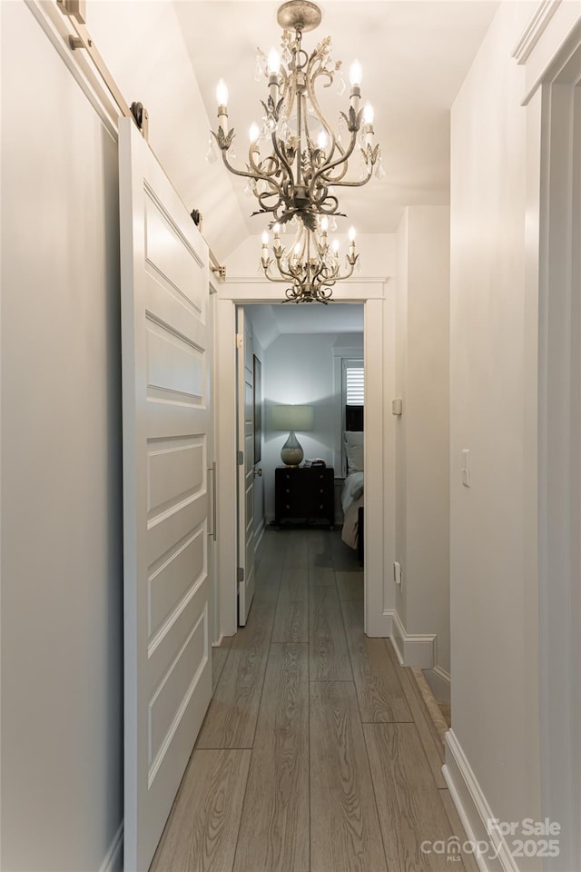 hall featuring hardwood / wood-style floors, lofted ceiling, and a chandelier