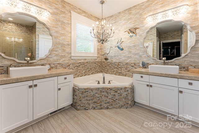 bathroom with hardwood / wood-style flooring, vanity, tiled bath, and a chandelier