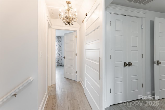 corridor with a chandelier and light hardwood / wood-style flooring