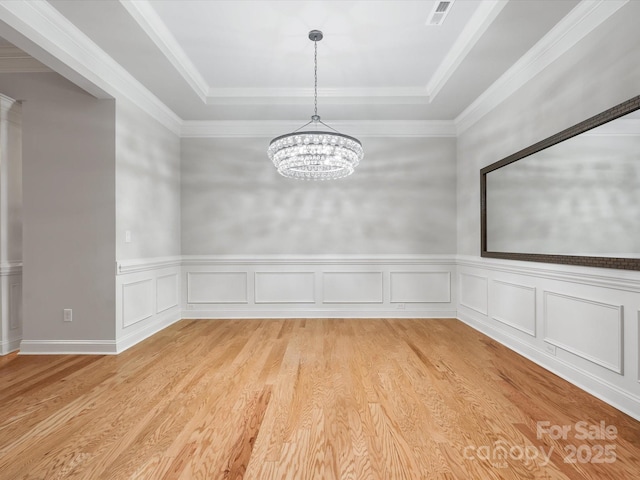 empty room with light wood-style floors, visible vents, a raised ceiling, and an inviting chandelier