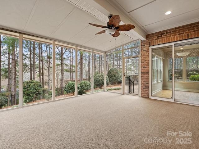 unfurnished sunroom with a ceiling fan and vaulted ceiling with beams