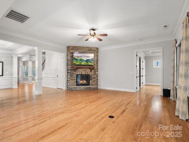 unfurnished living room with a fireplace, visible vents, ornamental molding, light wood-type flooring, and ornate columns