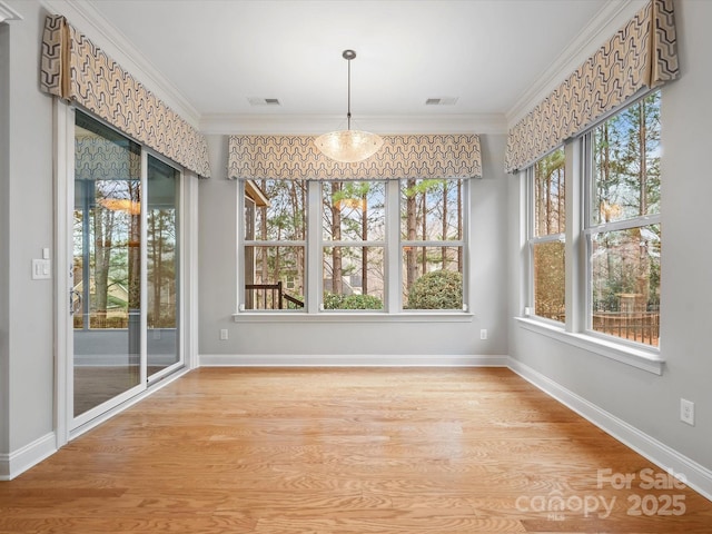 unfurnished dining area with light wood-style flooring, visible vents, ornamental molding, and baseboards