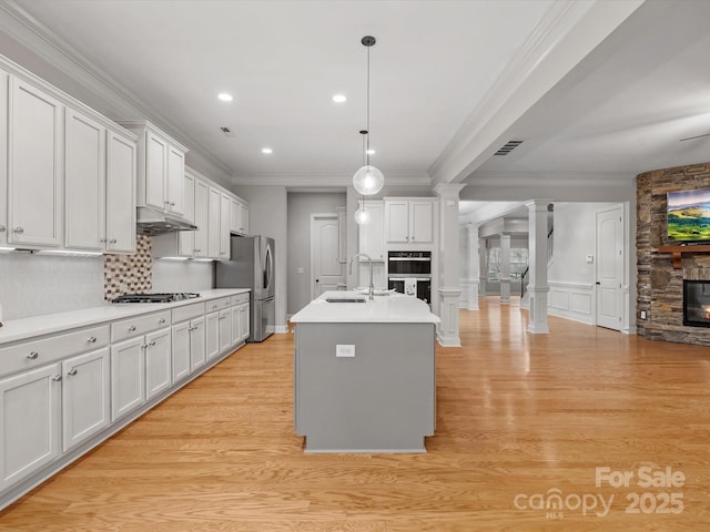 kitchen with a sink, visible vents, freestanding refrigerator, ornate columns, and crown molding