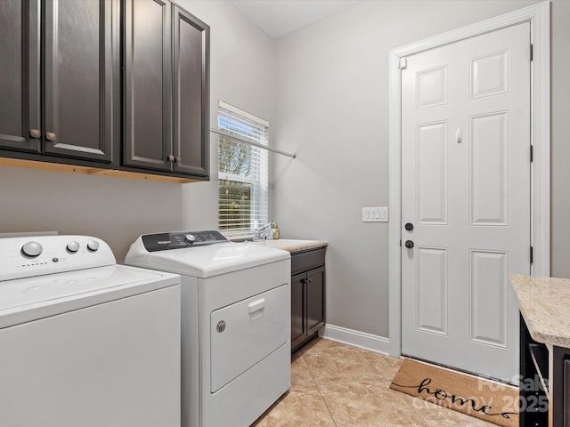 washroom with light tile patterned floors, a sink, baseboards, cabinet space, and washer and clothes dryer