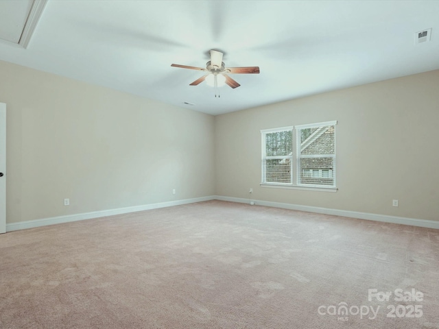 unfurnished room with visible vents, attic access, light carpet, ceiling fan, and baseboards