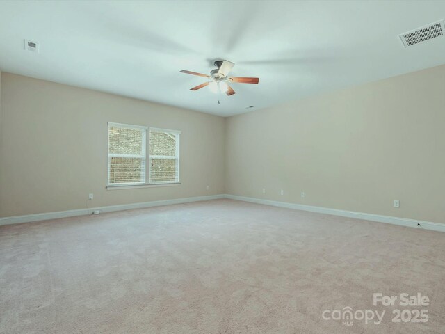 carpeted spare room with visible vents, ceiling fan, and baseboards