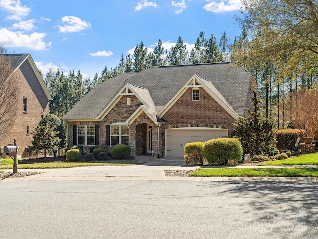 view of front of house featuring an attached garage, a shingled roof, concrete driveway, and brick siding