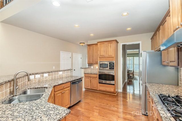 kitchen featuring stainless steel appliances, backsplash, light stone counters, and sink