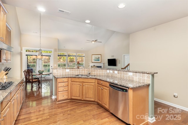 kitchen featuring ceiling fan, appliances with stainless steel finishes, decorative light fixtures, light stone countertops, and sink