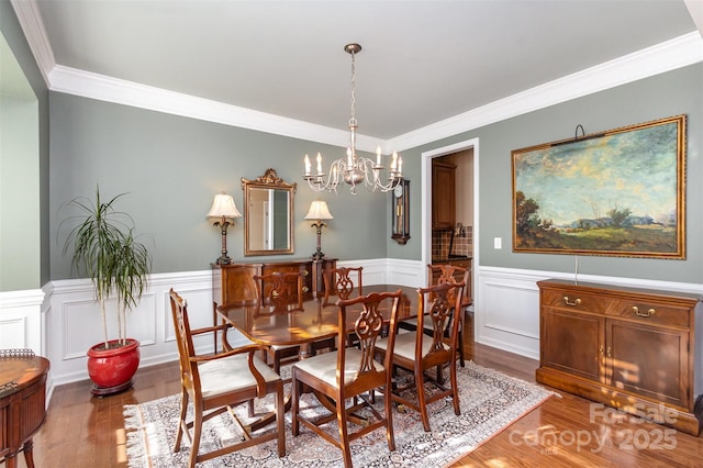 dining area featuring light wood-type flooring, a chandelier, and crown molding