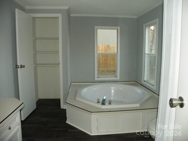 bathroom with a bathtub, vanity, crown molding, hardwood / wood-style floors, and toilet