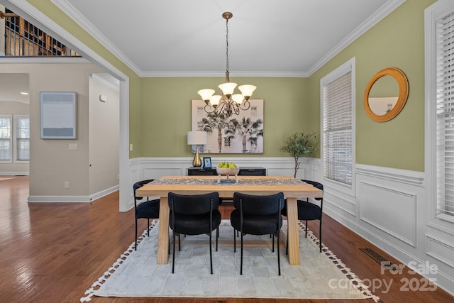 dining room featuring light hardwood / wood-style floors, crown molding, and an inviting chandelier