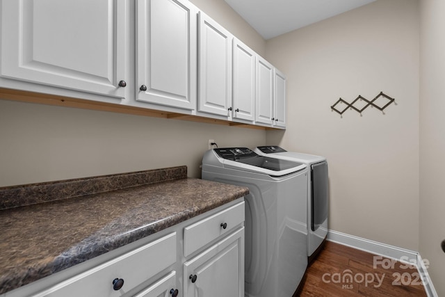 clothes washing area with cabinets, dark hardwood / wood-style floors, and washing machine and clothes dryer