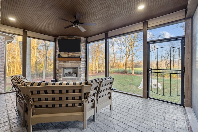 sunroom featuring ceiling fan, wood ceiling, and an outdoor stone fireplace