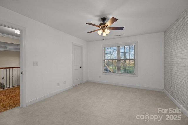 carpeted spare room with ceiling fan and brick wall