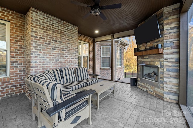 view of patio with an outdoor living space with a fireplace and ceiling fan