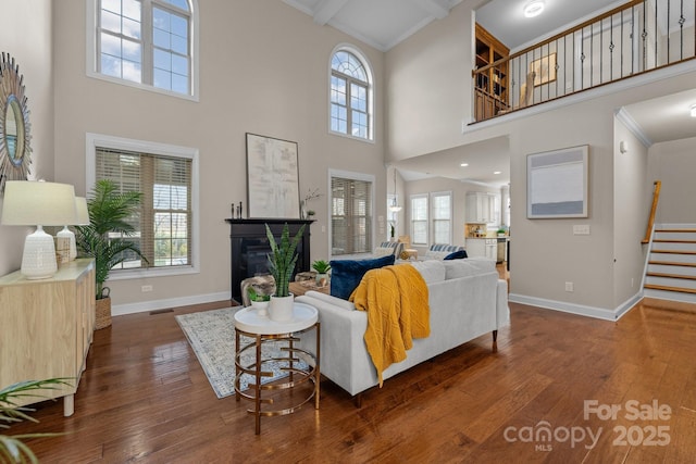 living room with beam ceiling, dark hardwood / wood-style flooring, and a high ceiling