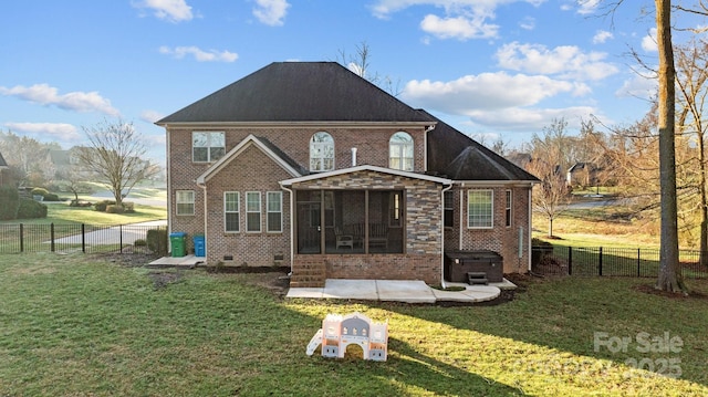 back of house featuring a sunroom, a hot tub, a patio area, and a lawn