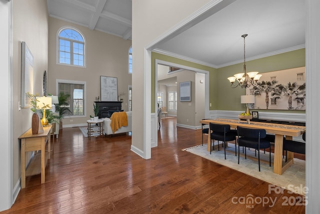 dining area with coffered ceiling, crown molding, hardwood / wood-style flooring, a notable chandelier, and beamed ceiling