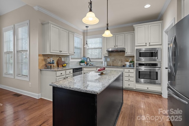 kitchen featuring white cabinetry, sink, pendant lighting, a kitchen island, and appliances with stainless steel finishes