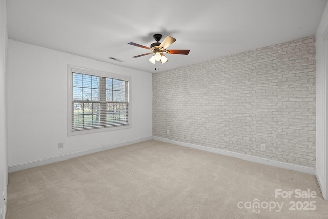 carpeted empty room featuring ceiling fan and brick wall