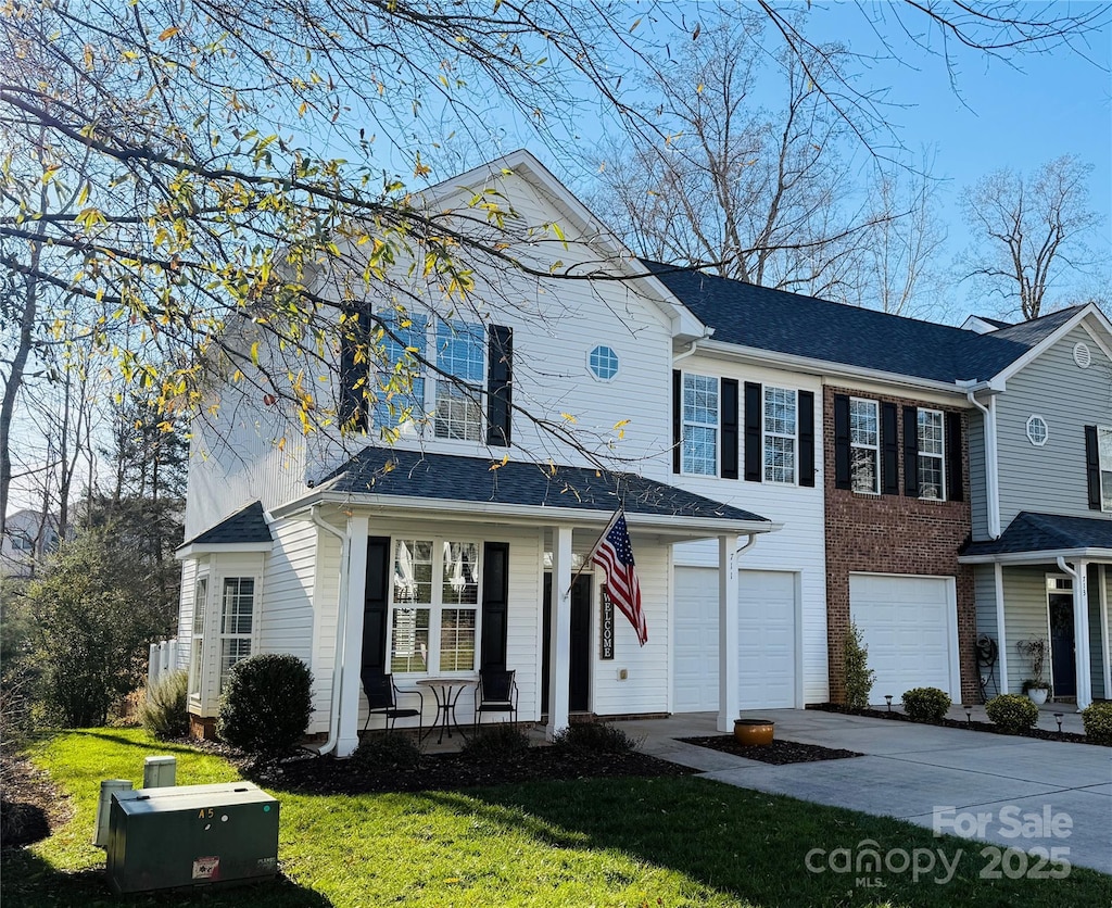 view of front of property featuring a porch, a front lawn, and a garage