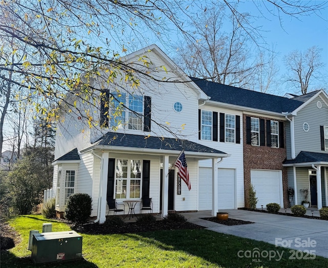 view of front of property featuring a porch, a front lawn, and a garage