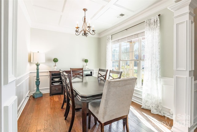 dining room with decorative columns, ornamental molding, coffered ceiling, hardwood / wood-style flooring, and a chandelier