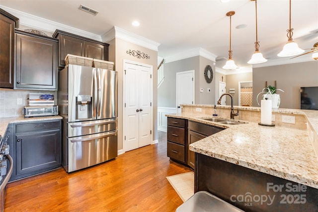 kitchen with pendant lighting, dark brown cabinets, sink, and stainless steel appliances