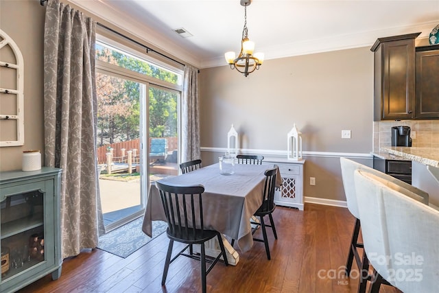 dining area with dark hardwood / wood-style floors, crown molding, and an inviting chandelier