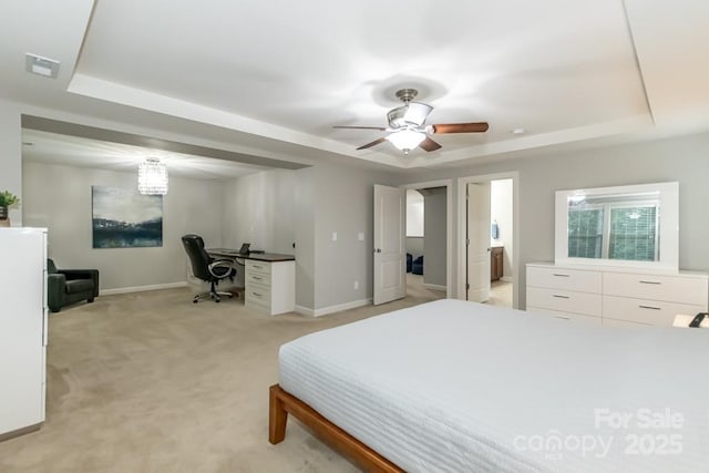 carpeted bedroom featuring ensuite bathroom, a raised ceiling, and ceiling fan