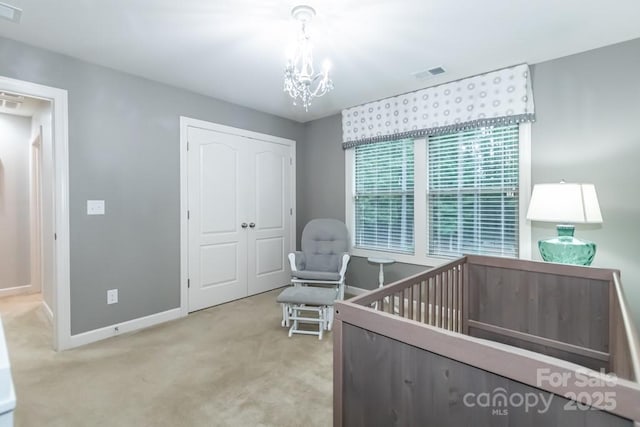 carpeted bedroom featuring a closet, a nursery area, and a notable chandelier