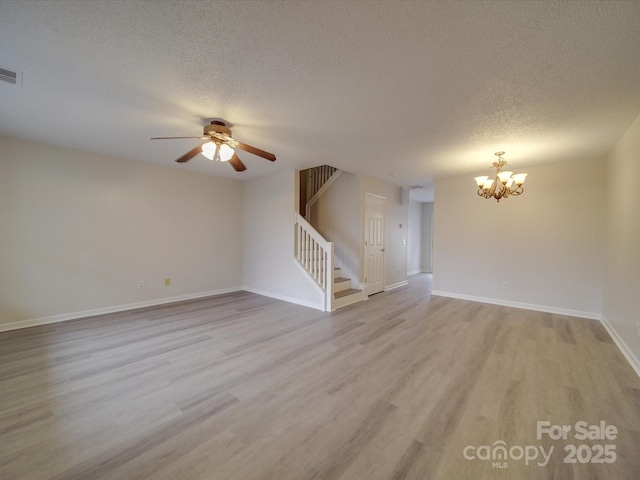 unfurnished living room featuring ceiling fan with notable chandelier, a textured ceiling, and light wood-type flooring